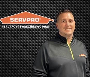 Man smiling on a dark background with the SERVPRO logo to his left 
