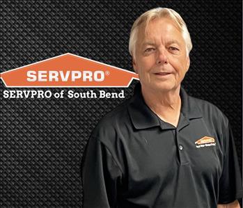 man smiling at the camera on a black background and a SERVPRO logo